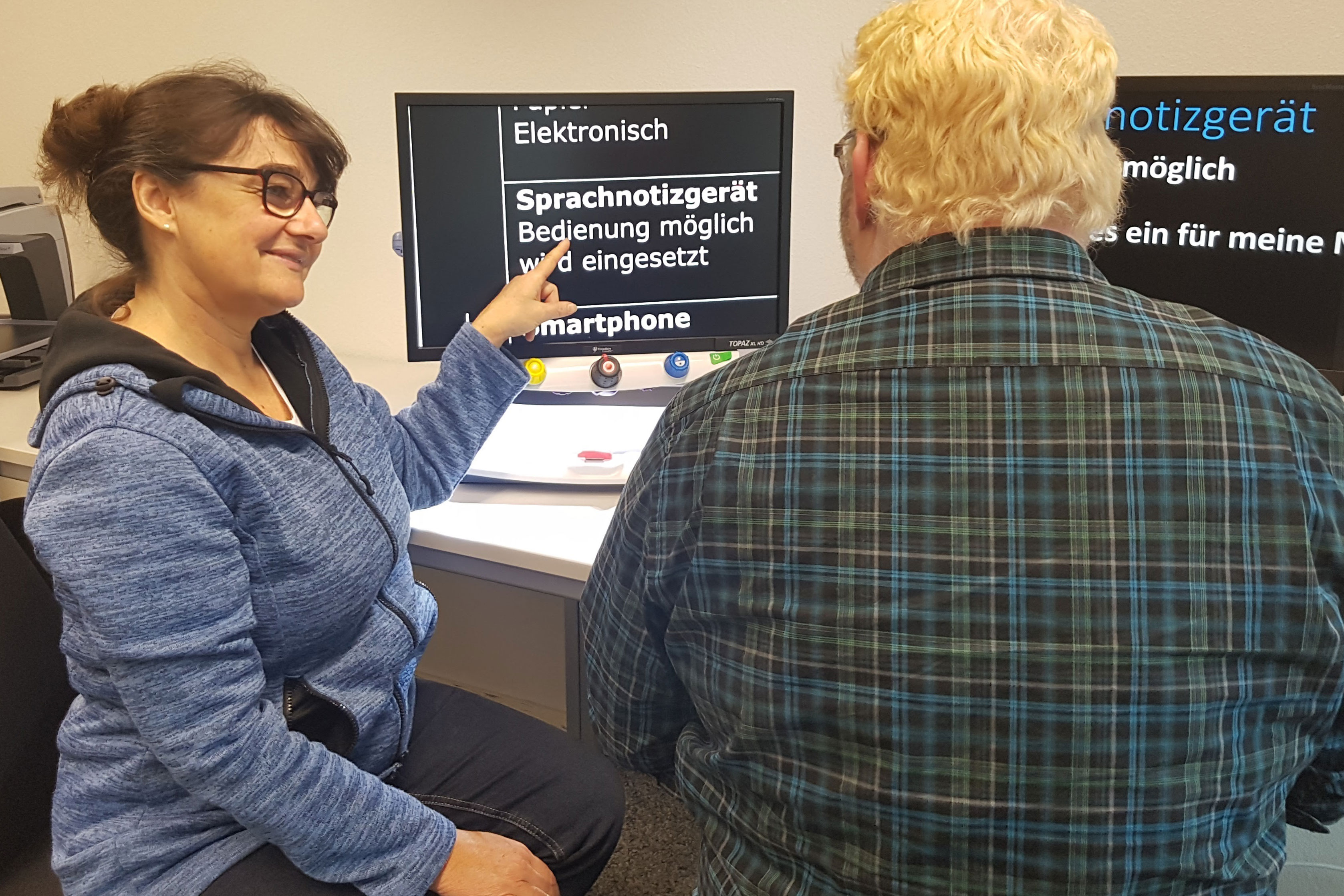 Beatrice Lippuner bei der Arbeit: Der Klient sitzt am PC und hat wegen der Blendung eine inverse Farbgebung und vergrösserte Schrift (= Zoomtext).